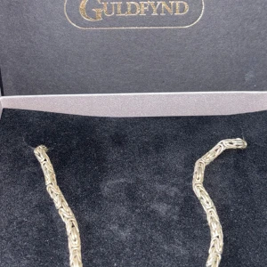 Silverhalsband från Guldfynd - Säljer ett snyggt silverhalsband från Guldfynd. Halsbandet är gjort av 925 sterling silver och har en vacker, flätad design som ger det en unik look. Halsbandet är 48cm och väger 63 g. Detta är äkta silver med Kvitto. Du får med paketet såklart och kvitto vid köpet. Perfekt för både vardag och fest!   