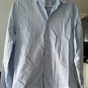 Filippa K skjorta - Säljer den stilrena skjorta från Filippa K i en ljusblå färg. Perfekt för sommaren eller till nästa fest. Är endast använd ett fåtal gånger och är i mycket bra skick. Den sitter som en medium.