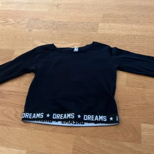 Långärmad croppad top - En croppad top med en rem där det står dreams.