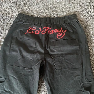ed hardy byxor - äkta ed hardy cargos, som tyvärr inte kommer till användning längre❤️ använda endast ett få tal gånger! extremt justerbara vid både midjan och längst ned med band (se tredje bilden). köpta för 1000kr❣️❣️