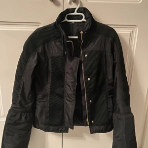 Svart jacka från Gucci by Tom Ford - Snygg svart jacka från Gucci med quiltade detaljer och dragkedja. Jackan har en hög krage och långa ärmar, perfekt för kyligare dagar. Tillverkad i Italien, vilket ger en känsla av lyx och kvalitet