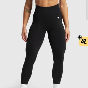 Gymshark tröningstights - Modell: Lift seamless leggings. Vid köp av 2 600kr har ett par marinblå i samma modell och storlek. Helt nya snygga svarta leggings från Gymshark med hög midja och perfekt passform. Tog tyvärr för liten storlek därav försöker bli av med dom. Perfekta för träning med en stilren design och diskret logga på sidan. Materialet är stretchigt och bekvämt, vilket ger bra rörelsefrihet.