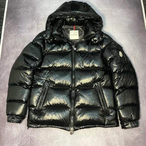 Moncler Maya - Letar du efter den perfekta jackan som kombinerar stil och funktion? Kolla in denna Moncler Maya! Den är inte bara en jacka, den är en livsstil. Med sin fantastiska värme och läckra design kommer du att känna dig som en modeikon på skidbacken eller en stjärna på stan. Den kommer garanterat att få dina vänner att undra hur du alltid ser så bra ut! Snabbt, innan den försvinner – slå till och bli den coolaste personen i rummet!