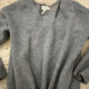 Grå ribbad tröja från Zara - Säljer en stilren grå ribbad tröja från Zara. Tröjan har en v-ringad design och långa ärmar, perfekt för kyligare dagar. Den är både bekväm och snygg, ett måste i garderoben!