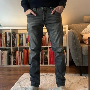 Slim glenn jack and jones jeans - Snygga grå jeans med en straight passform. De har en klassisk design med fem fickor och knappar. Perfekta för en avslappnad stil. Modellen heter slim glenn och är storlek 30/30. Jeansen har ett hål men går att fixas om man lämnar in på RepaMera! Personen på bilden är 170 och hör av er vid frågor och funderingar! Priset ej hugget i sten!