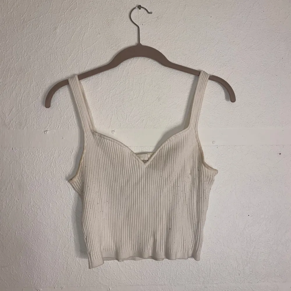 Säljer en stilren vit ribbad linnetopp med smala axelband. Toppen är croppad och har en enkel design som passar perfekt till sommaren. Perfekt för en avslappnad look.. Yläosat.