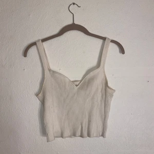 Vit ribbad linnetopp - Säljer en stilren vit ribbad linnetopp med smala axelband. Toppen är croppad och har en enkel design som passar perfekt till sommaren. Perfekt för en avslappnad look.