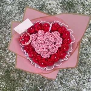 Hjärtformad bukett med rosor  - En vacker bukett formad som ett hjärta med röda och rosa rosor. Buketten är inslagen i rosa papper och dekorerad med ett pärlarmband. Perfekt som en romantisk gåva eller dekoration.