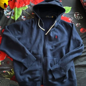Mörkblå hoodie från Polo Ralph Lauren  - Säljer en mörkblå hoodie från Polo Ralph Lauren, riktig fett med vita snören. Tröjan är i ganska bra skick skulle säga 6,7/10 storlek M passar S jag har S och passar bra på mig. Hör av er vid frågor 