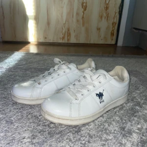Vita sneakers från Vinson Polo Club - Snygga vita sneakers från Vinson Polo Club med klassisk design t snörning. Skorna har en diskret logga på sidan och text på hälen. Perfekta för en stilren look.