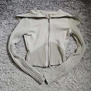 Zip up tröja - Snygg beige zip up tröja från BDG jeans/ urban outfitters med ribbade detaljer och dragkedja framtill. Tröjan har långa ärmar och en croppad, figurnärd passform. Säljs då den inte kommer till användning.
