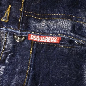 Mörkblå jeans från Dsquared2 - Snygga mörkblå jeans från Dsquared2 med klassisk femficksdesign och slitna detaljer. Jeansen har en knappgylf och kontrasterande sömmar som ger en cool look.