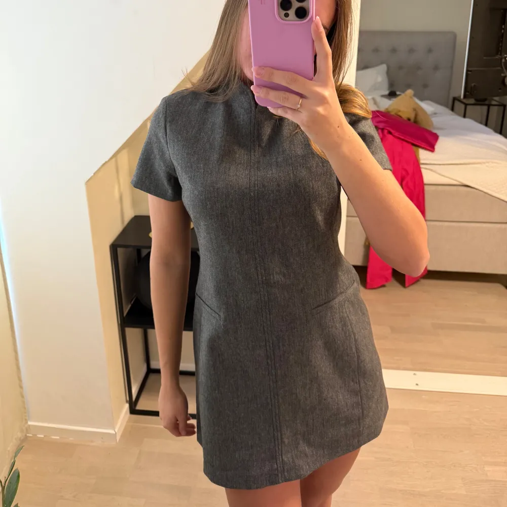 Snygg grå kortklänning med korta ärmar och en stilren design. Perfekt för en chic och minimalistisk look. Klänningen har en figurnära passform som framhäver silhuetten.. Mekot.