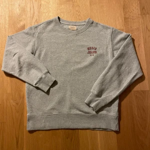 Nudie Collegetröja  - Säljer en stilren grå sweatshirt från Nudie Jeans i 100% ekologisk bomull. Skicket är grymt och tröjan är endast använd någon enstaka gång.