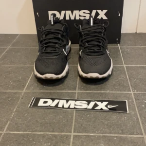 Svarta Nike sneakers D/MS/X - Snygga svarta Nike sneakers från D/MS/X-kollektionen. Skorna har en vit sula med grå detaljer och en tydlig vit Nike-logga på sidan. De är designade med snörning och har en modern look som passar perfekt för en urban stil.