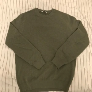Grön tröja från John Henric - Säljer en stilren grön tröja från John Henric. Tröjan har en klassisk design med rund hals och långa ärmar. Perfekt för en avslappnad och snygg look. Storlek M