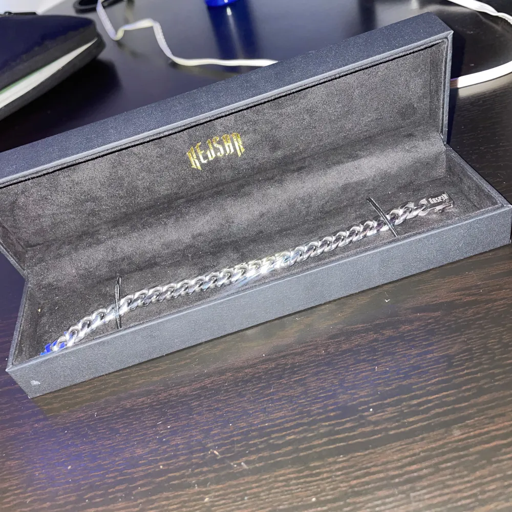 Stilrent silverfärgat pansarlänk armband från Kejsar. Armbandet har en robust design med breda länkar och en säker låsning. Perfekt för att ge en elegant touch till din stil. Den är 0,8mm i storlek och 60cm. Asusteet.