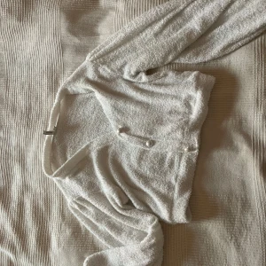 Vit kofta från Nelly - Säljer en mysig vit kofta med balongärmar från Nelly  i storlek S. Koftan har en fluffig textur och knappar framtill🤍