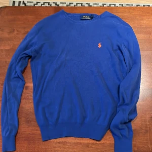 Blå tröja från Polo Ralph Lauren - Säljer en snygg blå tröja från Polo Ralph Lauren i slim fit. Tröjan är tillverkad i mjuk pima bomull och har en liten broderad logotyp på bröstet. Perfekt för en stilren look.