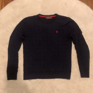 Morris tröja - Säljer en stilren mörkblå tröja från Morris i 100% merinoull. Tröjan har ett kabelstickat mönster, samt den röda morris loggan på bröstet. Tröjan är i storlek S och skick 10/10. Skriv vid fler frågor eller intresse👍