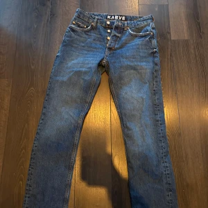 Blå jeans från Karve - Snygga blå baggy jeans från Karve med klassisk femficksdesign och knappgylf. Perfekta för du som skejtar. De har en rak passform och är tillverkade i slitstarkt denim.