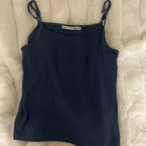 Mörkblå linnetopp från Lager 157 - Säljer en stilren mörkblå linnetopp från Lager 157. Toppen har smala axelband som är justerbara och är perfekt för varma dagar. Tillverkad i ett mjukt och bekvämt material. Vet inte exakt storlek men passar mig som använder xs.