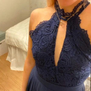 Mörkblå balklänning i spets  - Elegant mörkblå klänning med spetsdetaljer och hög hals. Klänningen har en öppen rygg och ett vackert fall. Uppsydd för mig som är 163 cm lång och endast använd en gång. Nypris 899kr. Hör av dig vid frågor eller fler bilder!💙💙 