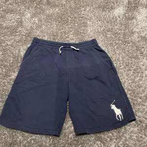 Mörkblå shorts med broderad logga - Snygga mörkblå shorts från Ralph Lauren med en stor broderad logga på benet. De har en bekväm passform med snörning i midjan och är perfekta för en avslappnad stil.