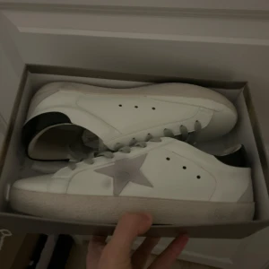 Vita sneakers med stjärndetalj - (Hark kvitto)Snygga vita sneakers med en grå stjärna på sidan och svarta detaljer vid hälen. Perfekta för en stilren look.