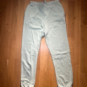  Ljusblå mjukisbyxor - Säljer ett par ljusa mjukisbyxor med resår i midjan och vid bensluten. Byxorna har en avslappnad passform och är perfekta för en bekväm dag hemma. De är tillverkade i ett mjukt material som känns skönt mot huden.
