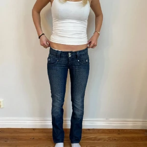 Blå jeans från Pepe Jeans - Snygga blå jeans från Pepe Jeans med låg midja och bootcut-stil. De har en klassisk femficksdesign och knappar fram. Perfekta för en avslappnad look.