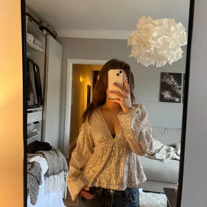 Glittrig topp med knytband - Säljer en glittrig topp från Nelly sååå fin och bara använd en gång. 