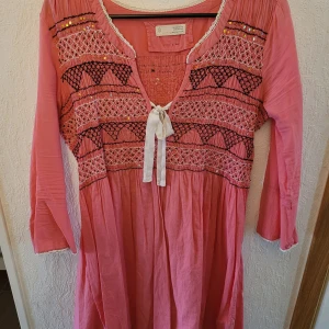 Rosa tunika från Odd Molly, stl 3 - Vacker rosa tunika från Odd Molly med vackra broderier och paljetter. Tunikan har knytning framtill med vitt sidenband och halvlånga ärmar. Hel och ren, inga djur i hemmet.