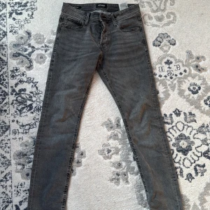 Grå jeansbyxor - Snygga grå jeansbyxor med en klassisk femficksdesign. De har en dragkedja och knapp framtill. Perfekta för en stilren look.