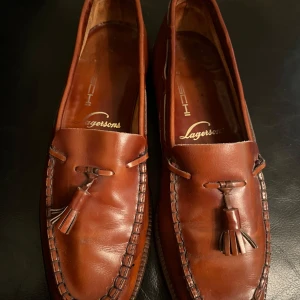 Bruna loafers från Lagersoms - Snygga bruna loafers från Lagersoms i skinn med dekorativa tofsar på ovansidan. Perfekta för en stilren look.