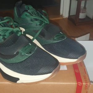 Nike sneakers i grönt och svart - Snygga Nike sneakers i grönt och svart med vita och bruna detaljer. Skorna har en modern design med snörning och en robust sula för extra komfort. Perfekta för en sportig look.