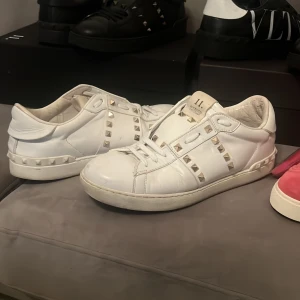 Vita sneakers med nitar från Valentino - Snygga vita sneakers från Valentino med ikoniska nitar som ger en edgy look. Skorna har en klassisk design med snörning och är perfekta för att lyfta vilken outfit som helst.