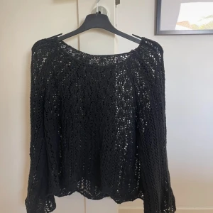 Svart stickad tröja - Säljer en svart stickad tröja med ett vackert hålmönster. Tröjan har långa ärmar och en rund halsringning. Perfekt på sommaren!