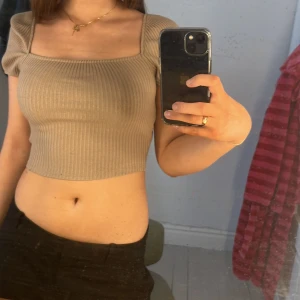 Beige ribbad croppad topp - Säljer en beige ribbad croppad topp med puff ärmar. Toppen har en fyrkantig halsringning och är perfekt för en trendig look. Den är både bekväm och stilren. Använd fåtal gånger💕