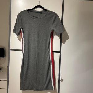 Grå klänning med ränder - Snygg grå klänning med korta ärmar och ränder i vitt och rött längs sidorna. 