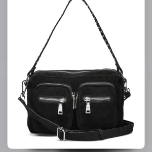 Svart axelväska med dragkedjor - Säljer min snygg svart axelväska i mocka med flera dragkedjor framtill, från Noella. Saknar den justerbara axelremen. 