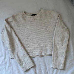 Beige stickad tröja från Zara - Säljer en stilren beige stickad tröja från Zara. Tröjan är croppad med långa ärmar och har en rund halsringning. Passar både Xs/S. 