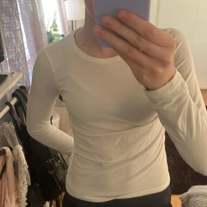 Vit långärmad topp - Säljer en stilren vit långärmad topp. Den är tight och passar perfekt för en enkel och snygg look. Toppen är gjord i ett mjukt material som känns skönt mot huden. Passar mig som har xxxxs-S.