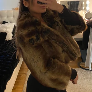Brun pälsjacka - Säljer en lyxig brun pälsjacka med en fluffig och varm känsla. Jackan har en elegant design med långa ärmar och en generös krage. Perfekt för att hålla sig varm och stilren under kyliga dagar.