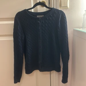 Mörkblå kofta  - Säljer en stilren mörkblå kofta med kabelstickat mönster. Koftan har långa ärmar och knappar framtill, perfekt för kyliga dagar. Ett klassiskt plagg som passar till mycket. 💙