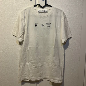 Vit t-shirt från Off-White - Säljer en vit t-shirt från Off-White med svart text och grafik på framsidan. Baksidan har ett stort grönt och svart grafiskt mönster. Perfekt för dig som gillar streetwear och vill ha något unikt i garderoben. Tröjan är lite missfärgad under armarna. Hör av er vid frågor 😁