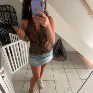 Leopardmönstrad topp från Zara - Snygg leopardmönstrad topp från Zara i en härlig brun och svart färgkombination. Toppen har en djup v-ringning och knytning i midjan för en stilren look. Perfekt för att ge din outfit en trendig touch.