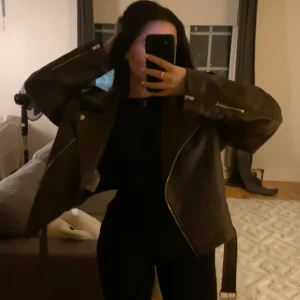 Olivgrön skinnjacka från Gina tricot  - Snygg olivgrön skinnjacka från Gina tricot med dragkedja och kanopar . Jackan har en croppad design och axelklaffar för en cool look. Perfekt för att ge din outfit en edgy touch.