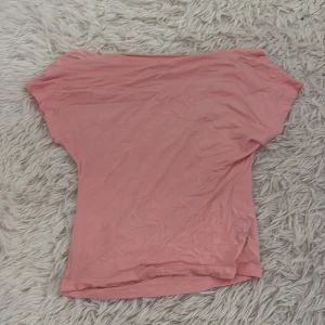 Rosa kortärmad topp - Säljer en enkel och stilren rosa topp med korta ärmar. Perfekt för en avslappnad look. Toppen är gjord i ett mjukt och bekvämt material.