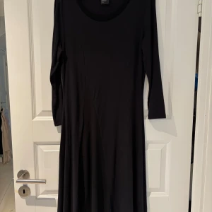 Svart bomullsklänning från Armani Exchange - Elegant svart knälång klänning från Armani Exchange med långa ärmar. Perfekt för en stilren look. Tillverkad i ett mjukt och bekvämt bomullsmaterial som ger en fin passform.